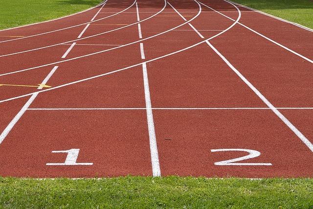 Leerer Leichtathletikbahn mit roten Bahnen und markierten Startnummern 1 und 2 im Vordergrund.