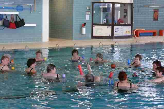 Gruppentraining im Wasser: Frauen mit Schwimmnudeln und B&auml;llen stehen in einem Schwimmbecken.