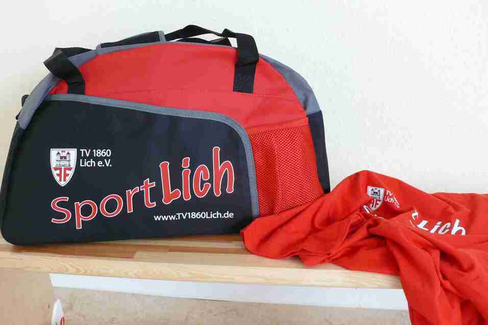 Schwarze Sporttasche mit roten Akzenten und einem roten T-Shirt daneben, beschriftet mit "SportLich".